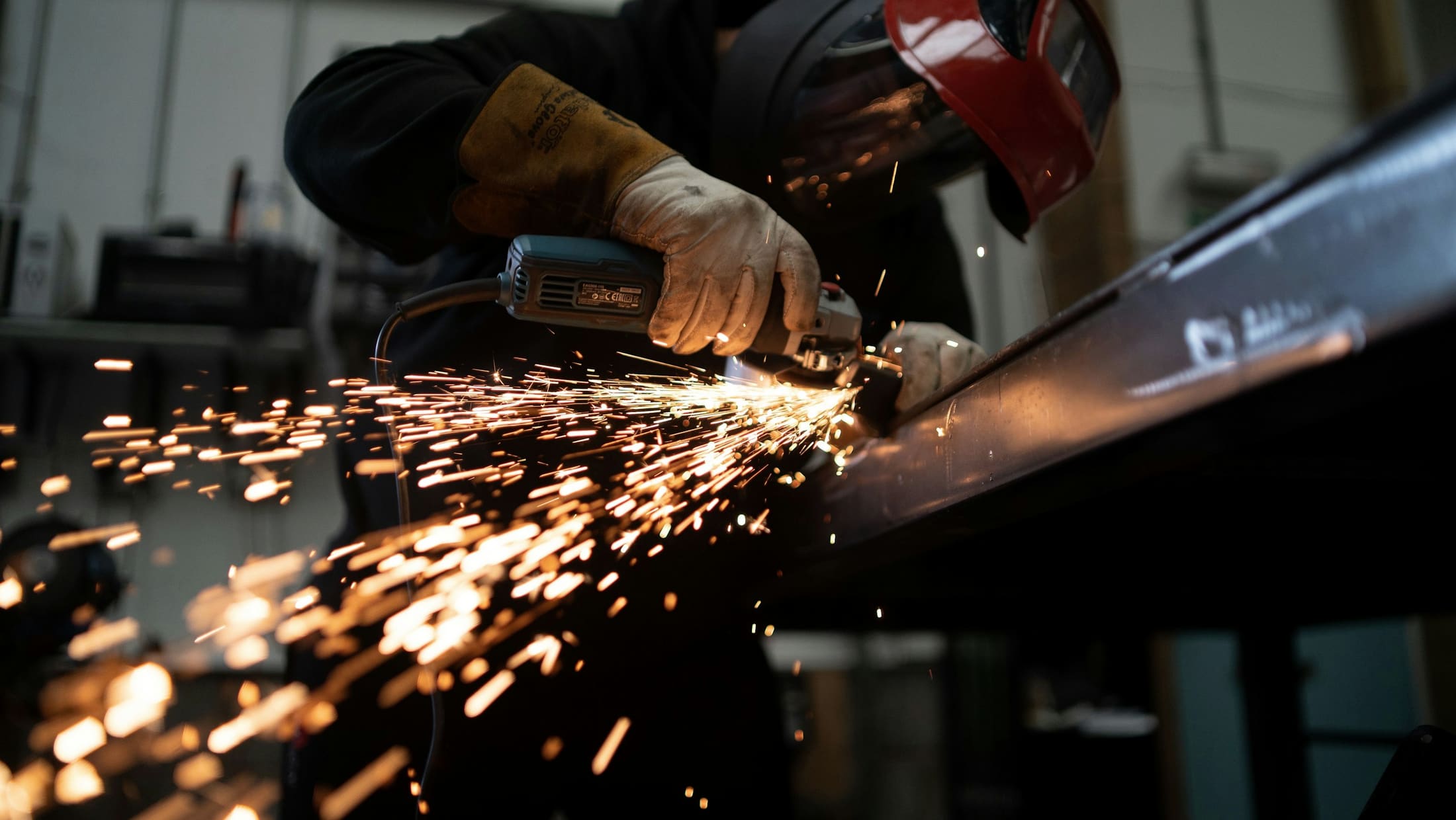 Angle grinder throwing a shower of sparks across a steel workpiece